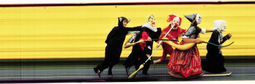 Children in Halloween Costumes Running Together with Hands on Shoulder of Person in Front on Them