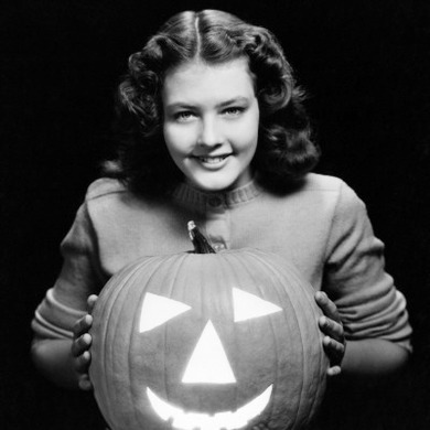 Teenage Girl Standing Behind Halloween Jack-O-Lantern, Smiling